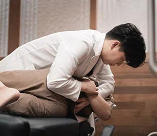 설명한의원 진료실에서 한의사가 베드에 누운 환자에게 휜다리(O다리·X다리) 교정을 위한 도수 처치를 시행하는 모습